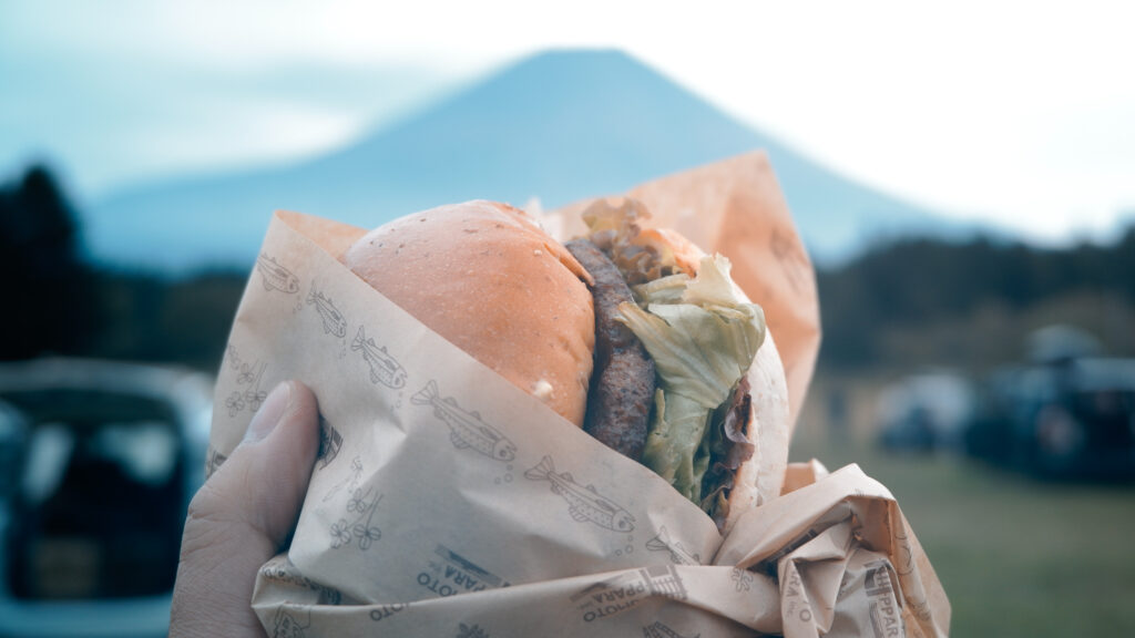 テイクアウトし富士山の前でバーガーにかぶりつく
